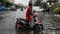Banjir membuat motor seorang pengendara mogok akibat terendam air.