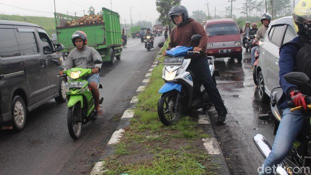 Porong banjir, biker melintas di pembatas jalan/