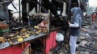 Seorang pedagang melihat rukonya yang telah hangus dilalap api. Ia mengumpulkan sejumlah dagangannya yang masih dapat diselamatkan.