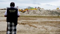 Seorang pecalang tampak memantau aktifitas di proyek perluasan bandara untuk memeriksa dan mengecek alat berat serta para pekerjanya.