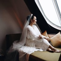 Bergaya di depan jendela kapal pesiar menjelang pemberkatan pernikahannya, Yuanita tampil cantik dan elegan dalam balutan bride robe dari Bride Kit.Foto: Axioo/Instagram @yuanitachrist