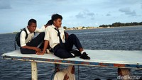 Sejumlah penumpang yang tak kebagian tempat di dalam perahu pun nekat duduk di atap kapal untuk bisa menyeberang pulau.