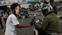 Mereka juga membagikan bunga kepada pengendara yang melintas.