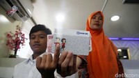 Orang tua dan anak yang kompak menunjukan buku tabungan Simpel usai mendaftarkan dan membuka rekening untuk sang anak belajar menabung.
