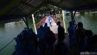 Beberapa siswa berlarian untuk menaiki perahu eretan di Situ Rawa Gede.