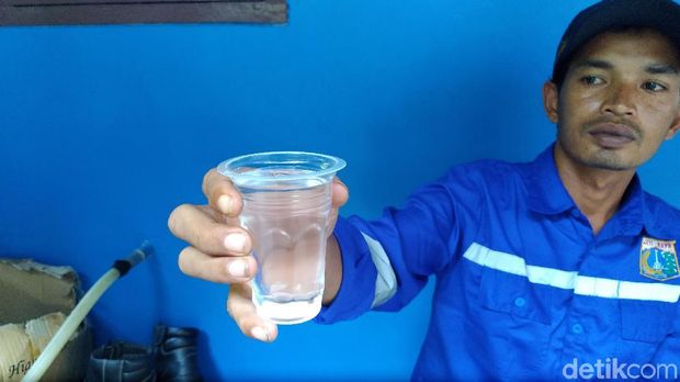 Suwarjo menyodorkan air minum produk instalasi BWRO di Pulau Pramuka.  