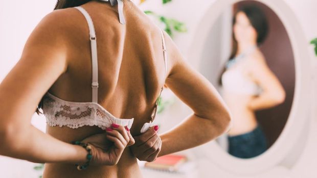 Sexy woman closing her bra in front of the mirror, close-up