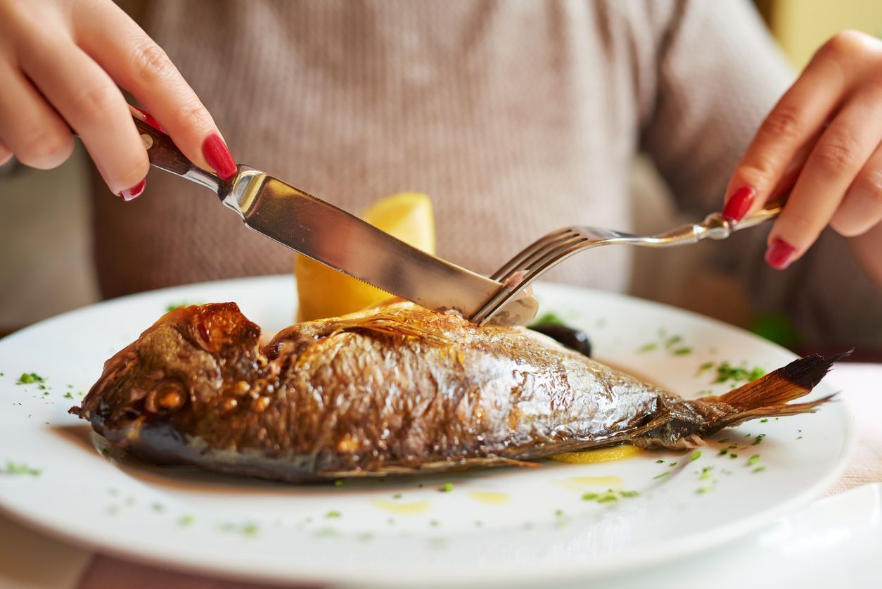 woman hands eating fish at restaurant, having her lunch.