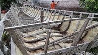 Seorang perajin mendempul lambung perahu agar tidak bocor usai dikerjakan dan sebagai tahap proses finishing.