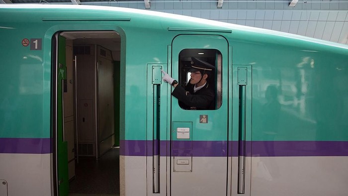 TOKYO, JAPAN - MAY 02:  A train guard gestures as he leans out of a window on a Shinkansen bullet train at Tokyo Train Station on May 02, 2016 in Tokyo, Japan. The Shinkansen is a network of high-speed railway lines in Japan currently consisting of 2,764.6 km (1,717.8 mi) of lines with maximum speeds of 240-320 km/h (150-200 mph). The network presently links most major cities on the islands of Honshu and Kyushu, and Hakodate on northern island of Hokkaido. The maximum operating speed is 320 km/h (200 mph) though test runs have reached up to a world record 603 km/h (375 mph) for maglev trains in April 2015.  (Photo by Carl Court/Getty Images)