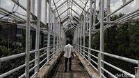 Seorang warga melintas di jembatan penyeberangan orang yang rusak.