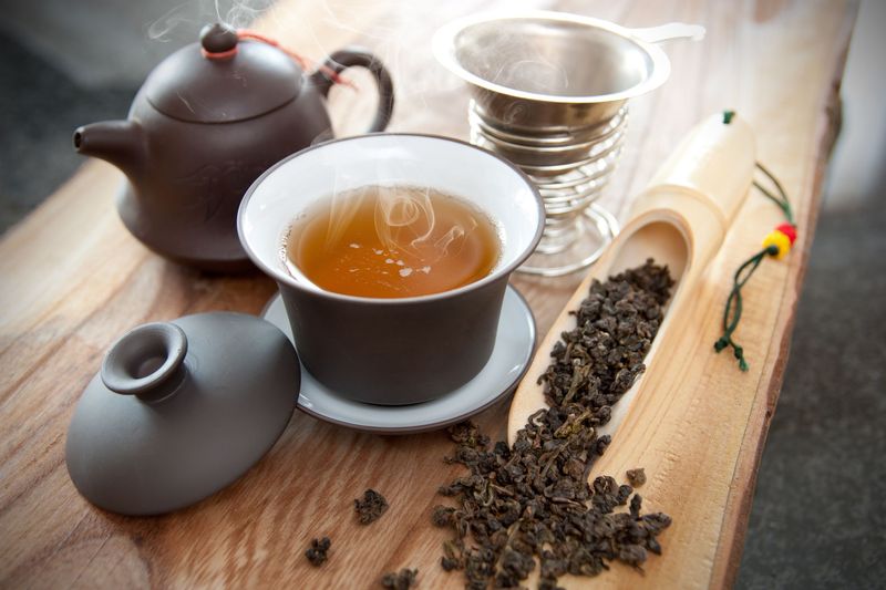 Teh untuk Lemak Perut cup of herbal tea with chamomile flowers on a wooden table