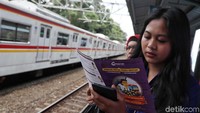 Sambil menunggu Commuter Line para penumpang menyempatkan membaca selebaran yang diberikan.