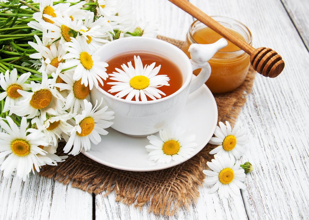cup of herbal tea with chamomile flowers on a wooden table