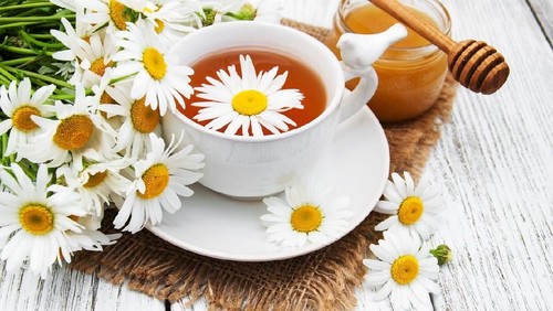 cup of herbal tea with chamomile flowers on a wooden table