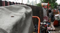 Seorang warga membuang sampah melewati pagar pembatas rel kereta api.