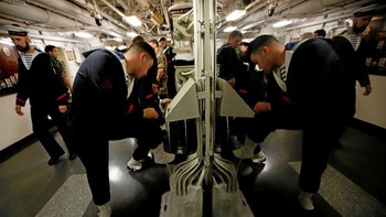 Para pelaut memeriksa sepatu masing-masing di dalam kapal induk Charles de Gaulle. Foto: Reuters
