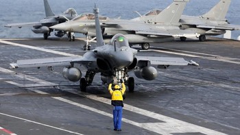 Petugas sedang mengarahkan pesawat jet yang akan lepas landas di tengah lautan. Foto: Reuters