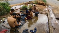 Sulitnya mendapatkan air bersih membuat warga nekat mandi di gorong-gorong jalan San Felix, Venezuela. William Urdaneta/Reuters.