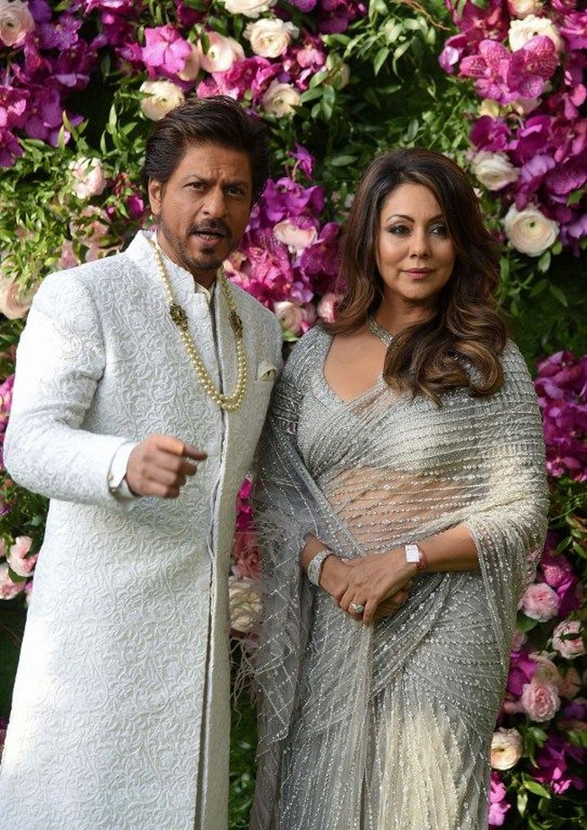 Shah Rukh Khan berpose bersama sang istri yang juga seorang produser Gauri Khan. Keduanya tampil kompak dalam balutan warna perak. Foto: SUJIT JAISWAL / AFP