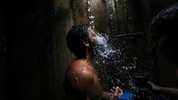 Warga menggunakan air dari pipa bawah tanah di kota Caracas untuk mandi dan mengumpulkan air bersih. Ivan Alvarado/Reuters.