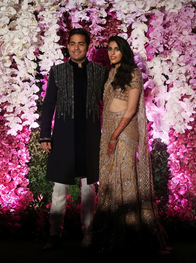 Upacara pernikahan dilanjutkan dengan resepsi di lokasi yang sama. Kali ini Akash dan Shloka mengenakan busana yang lebih santai namun tetap mewah. Pria 27 tahun tersebut terlihat memakai tunik hitam bertabur payet, sang istri berbusana sari yang juga dipenuhi payet berkilauan. Foto: REUTERS/Francis Mascarenhas