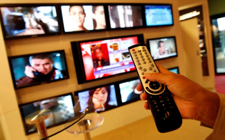 FILE PHOTO: A visitor uses a remote control as she looks at television programmes during the annual MIPCOM television programme market in Cannes, southeastern France, October 4, 2010. REUTERS/Eric Gaillard/File Photo