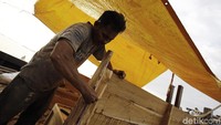 Seorang pekerja sedang memasang bangku kayu, kapal yang dibuat ini merupakan jenis pinisi untuk wisata.