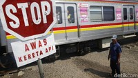 Seorang warga menjaga perlintasan kereta api di kawasan Pondok Cina, Depok, Jawa Barat, Jumat (15/3/2019).