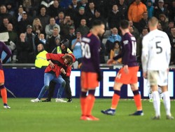 Laga sendiri sempat terinterupsi karena ada penonton yang menerobos ke lapangan. Petugas lapangan berusaha mengamankannya. (Foto: Marc Atkins/Getty Images)