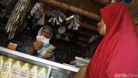 Hj. Mulfiati melayani tarik tunai seorang nasabah.