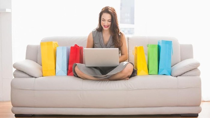 Woman Sitting On Couch Doing Online Shopping On Laptop