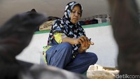 Seorang Ibu nampak sibuk mengecat patung Komodo.