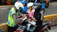 Polisi memeriksa kelengkapan surat kendaraan bermotor salah satu pengendara.