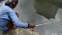 Seorang warga sedang memancing di kali yang berada di kawasan Gunung Sahari, Jakarta, Senin (18/3/2019).