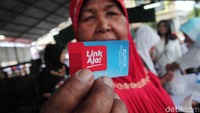 Seorang warga memperlihat kupon Link Aja saat membeli paket pangan murah.
