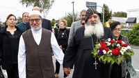Mereka kemuian berjalan menuju lokasi penembakan di Masjid Christchurch, Selandia baru. Sang pastor terlihat membawa karangan bunga. REUTERS/Edgar Su.