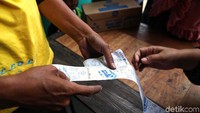 Seorang warga menunjukkan struk pembayarannya saat membeli sembako murah.