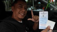 Warga menunjukan hasil uji emisi mobilnya.