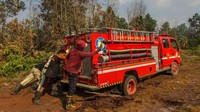 Petugas gabungan dari Pemadam Kebakaran dan Badan Penanggulangan Bencana Daerah (BPBD) Kota Pekanbaru berusaha mengeluarkan mobil pemadam yang terpuruk ketika akan memadamkan kebakaran lahan gambut di Pekanbaru, Riau, Senin (18/3/2019). ANTARA FOTO/Rony Muharrman.