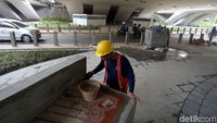 Seorang petugas sedang sibuk mengerjakan salah satu bangku taman yang berada di kolong Jembatan Semanggi tersebut.