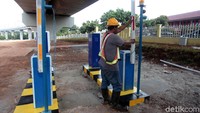 Lahan parkir itu masih dalam tahap pembangunan. Nampak pekerja sedang memasang palang otomatis di sekitar lahan parkir tersebut.