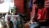 Seorang perajin nampak sedang mengerjakan miniatur ondel-ondel di kawasan Banjir Kanal Timur, Jakarta, Rabu (20/3/2019).