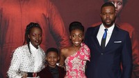 Lupita tampil chic dengan dress transparan berbalut kemeja putih. Jamie McCarthy/Getty Images