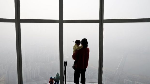 Seorang wanita menggendong bayinya di pelukannya melihat pemandangan Seoul diselimuti oleh debu halus selama hari yang tercemar di Seoul, Korea Selatan, 6 Maret 2019. (REUTERS / Kim Hong-Ji)