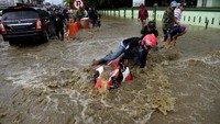 Seorang pemotor tampak terjatuh saat berusaha menerobos banjir. ANTARA FOTO/Zabur Karuru.