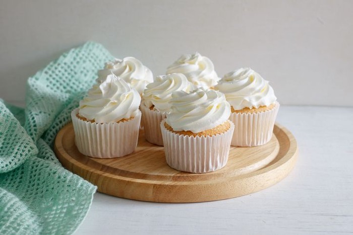 sweet vanilla cupcake with buttercream put on wooden board, image soft tone.