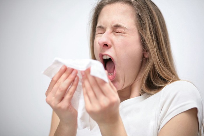 bersin portrait of a young woman with tissue sneezing
