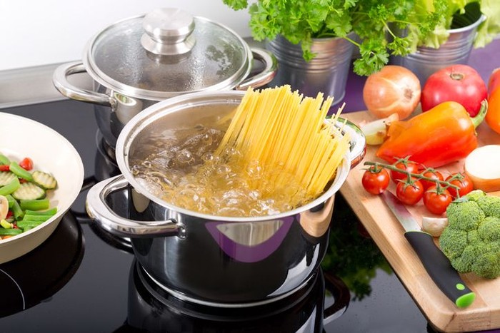 pan of boiling water with spaghetti on the cooker in the kitchen