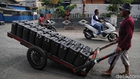Seorang pedagang menyusuri jalan untuk menjajakan air bersih.